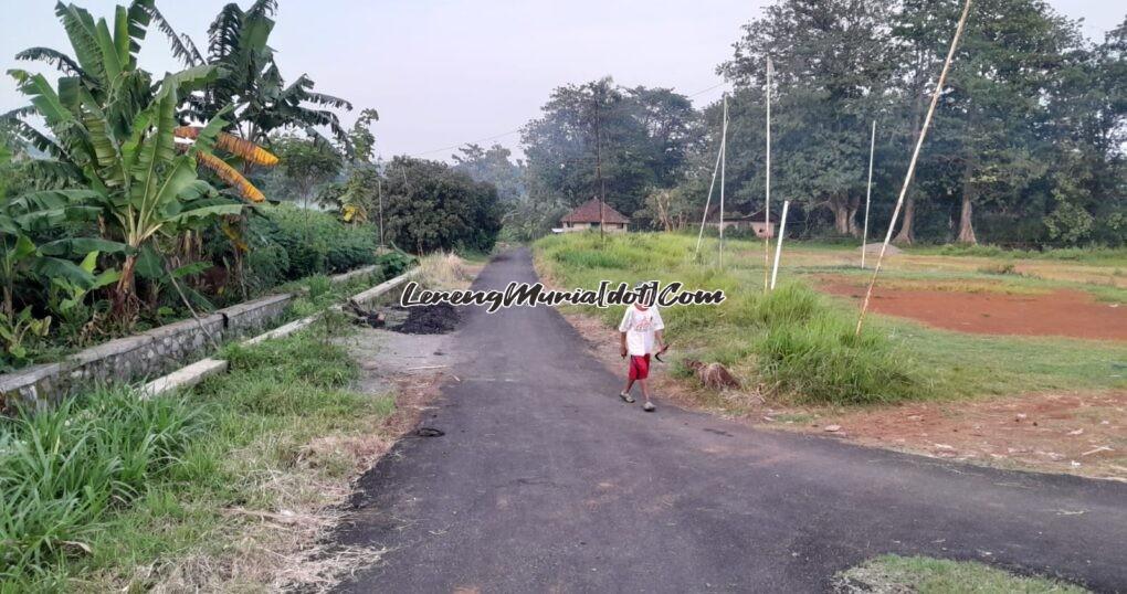 Foto seorang penduduk melewati jalan yang baru diaspal