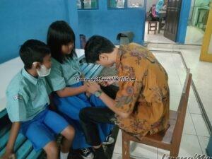 Foto pemotongan kuku siswa oleh guru