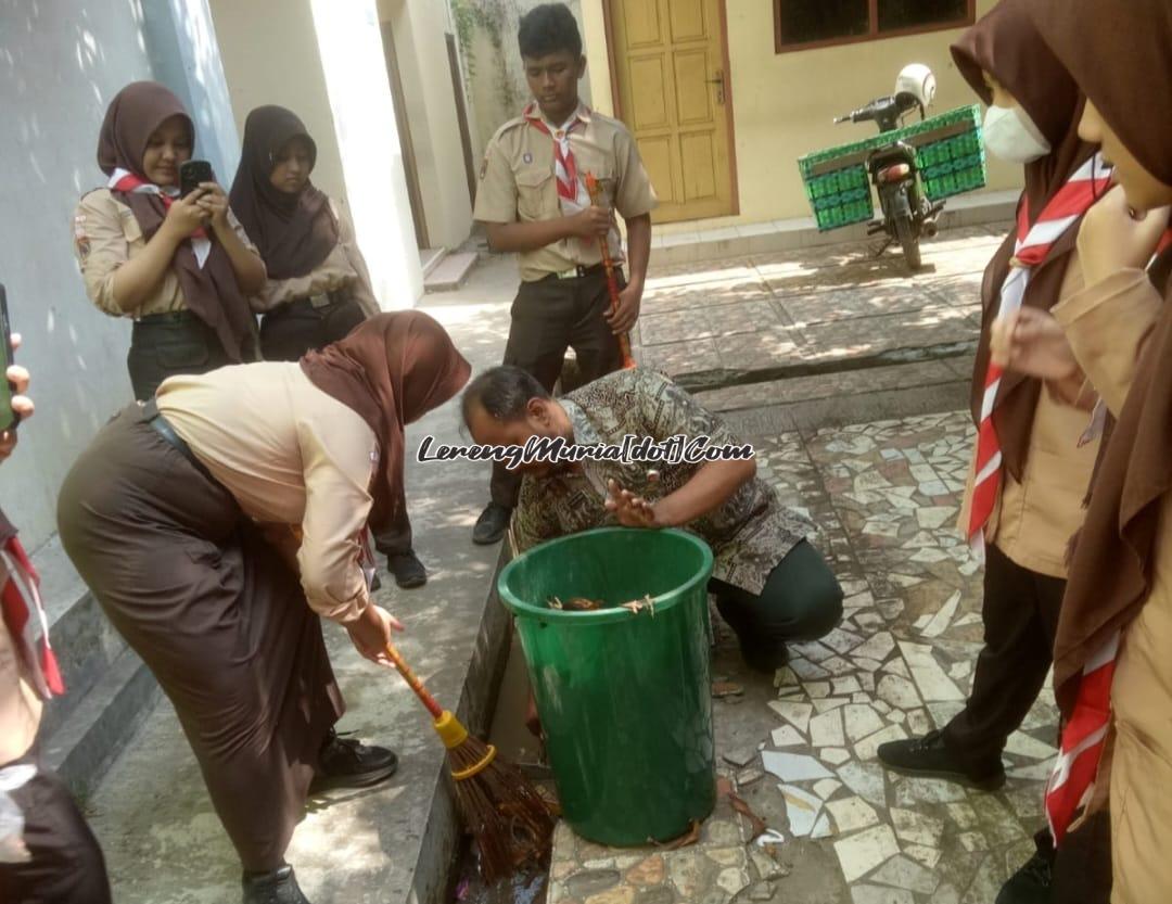 Foto guru dan siswa sedang membersihkan selokan