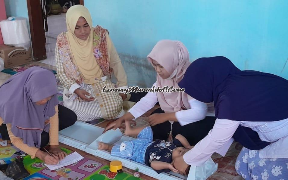 Foto Bidan Ida (2 dari kanan) sedang menimbang balita dibantu oleh kader posyandu