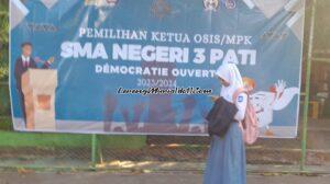 Foto seorang siswa sedang melewati banner yang dipasang untuk acara Pemilos/MPK di Lapangan Basket SMAN 3 Pati