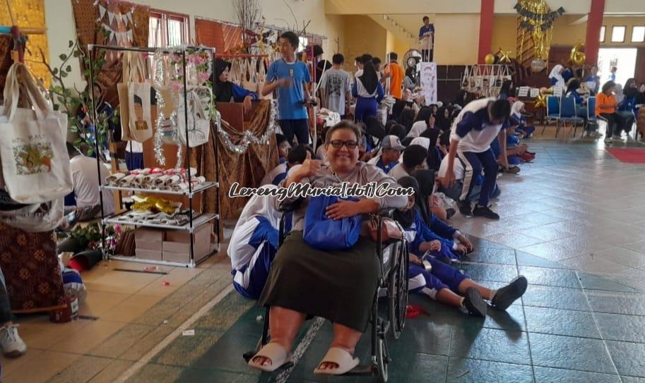 Foto Ibu Natalie Nugraheni, M.Si. dengan bantuan kursi roda mendampingi kelasnya