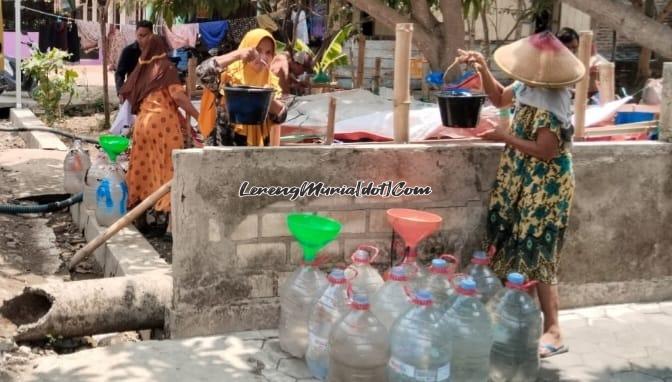 Foto warga Desa Tondokerto sedang memindahkan air  dari  penampungan ke wadah  yang sudah disiapkan