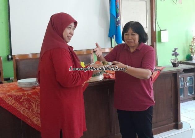 Foto Dra. Siti Rukmi Murni (kiri) menerima potongan tumpeng dari Siti Wahyuningsih, M.Pd. dengan penuh kehangatan