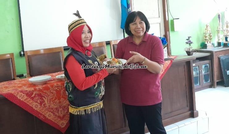 Foto Siti Wahyuningsih, M.Pd. sedang menyerahkan potongan tumpeng kepada Mujiannie, S.Pd., M.Si. (kiri) dengan wajah ceria