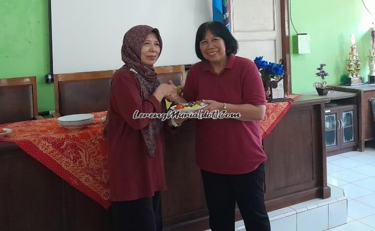 Foto Dra. Juleha Retnowati (kiri) menerima potongan tumpeng dari Siti Wahyuningsih, M.Pd. dalam acara HGN 2023 di ruang guru