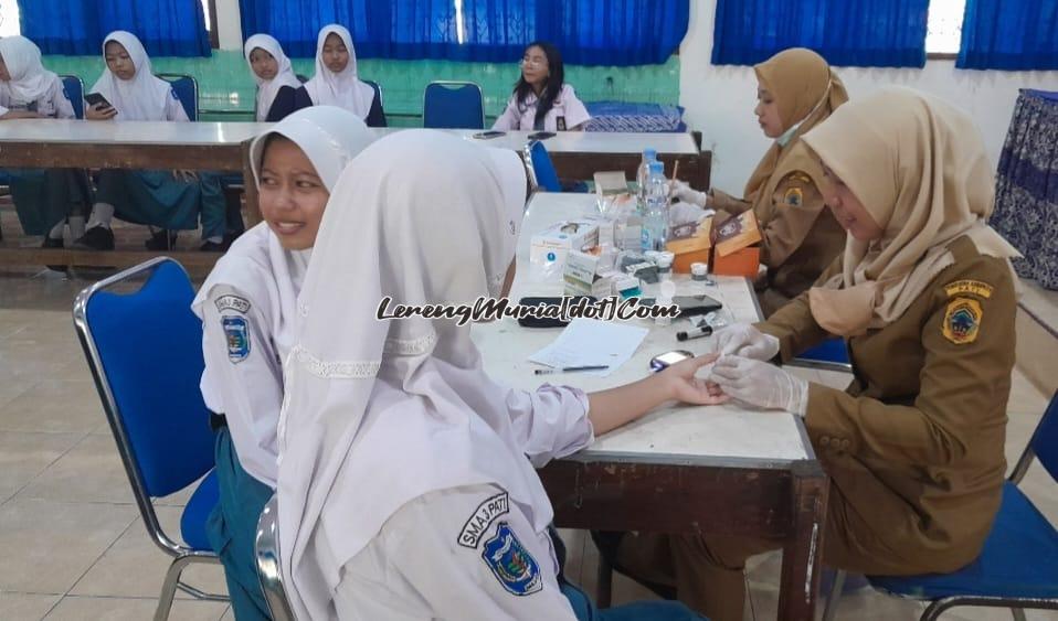 Foto Umi Yuli Purwanti, S.Gz. (kanan) petugas dari Puskesmas Pati I sedang mengambil sample darah salah satu siswa putri SMAN 3 Pati