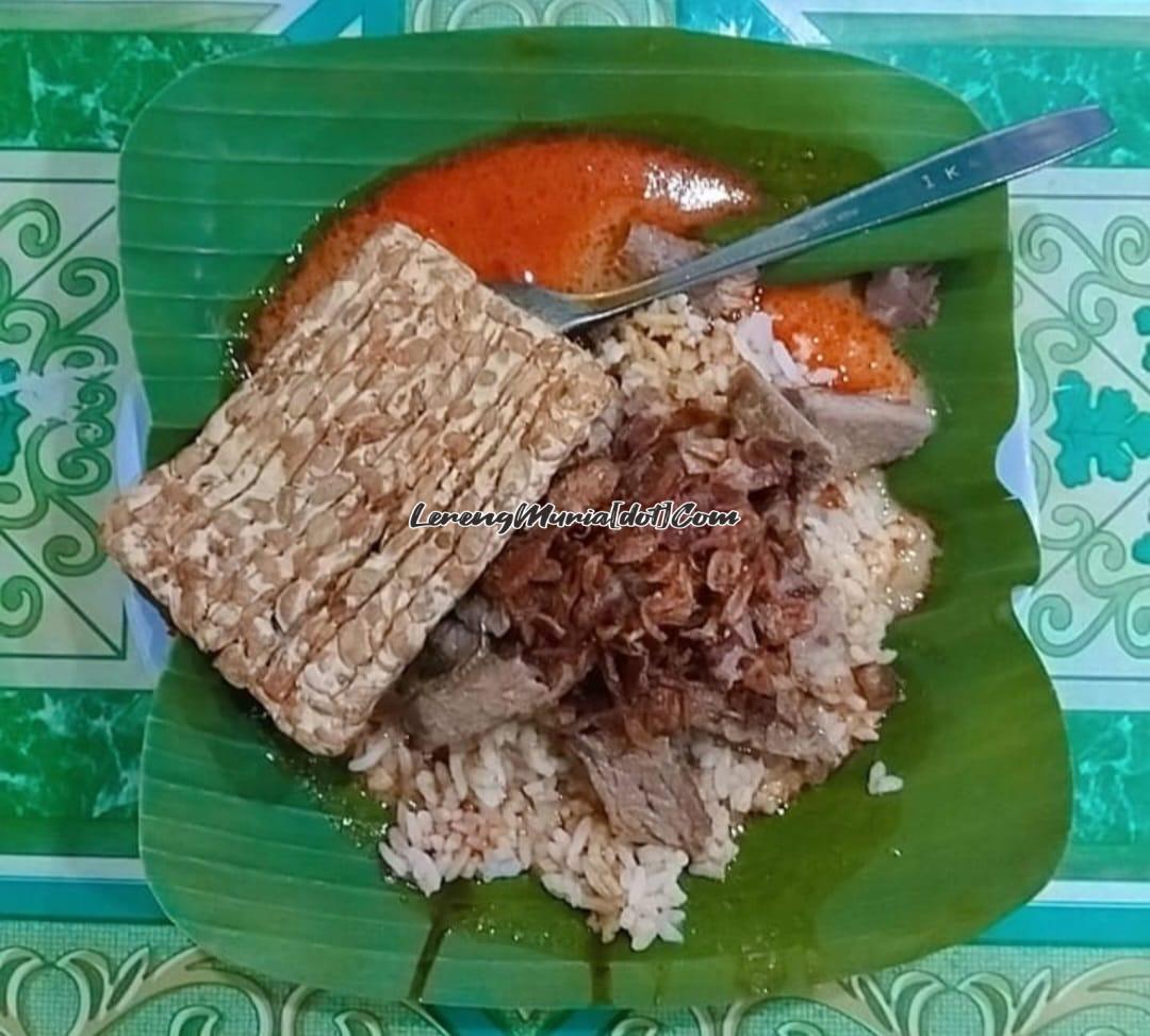 Foto satu porsi nasi gandul yang dilengkapi tempe, daging dan alas daun pisang sebagai salah satu ciri khasnya