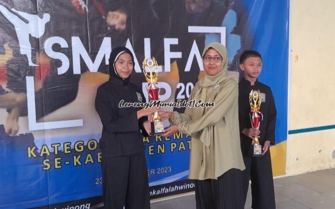 Foto penyerahan piala pesilat terbaik putri oleh Anggun Kusuma Dewi, S.Pd. Staf Kesiswaan Sekbid Ekstrakurikuler  SMK Al Falah Winong (kanan) kepada Khairaini Zalfa Nur Laili (kiri) dari SMPN 1 Juwana