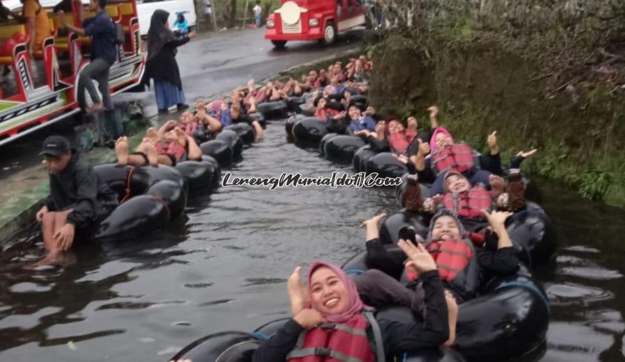 Foto peserta tubing Kali Pucung sedang melewati jalur landai sambil menikmati dinginnya air pegunungan