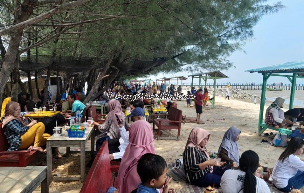 Pengunjung sedang duduk santai menikmati rindang dan teduhnya pohon cemara di pinggiran Pantai Wates