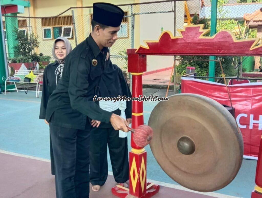 Ketua Cabang SH Terate Pati Abdul Khalim, M.M., M.Pd.I. sedang memukul gong sebagai tanda pembukaan Kejuaraan Piala Ranting Wedarijaksa