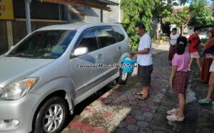 Supri (kiri) sedang menyiram mobil baru dengan air yang berisi uang logam dan kembang/nyebar udhik-udhik