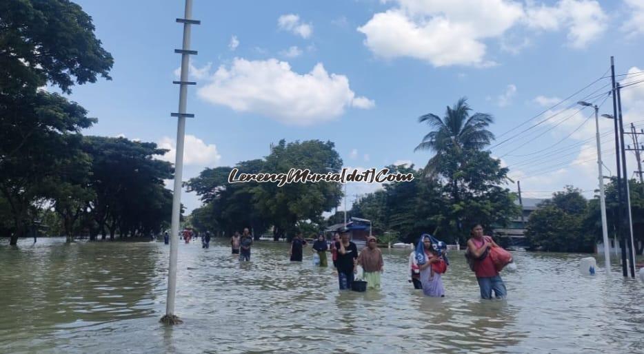 Pengungsi membawa barang bawaan berjalan diantara derasnya arus menuju ke arah barat (Kota Demak)