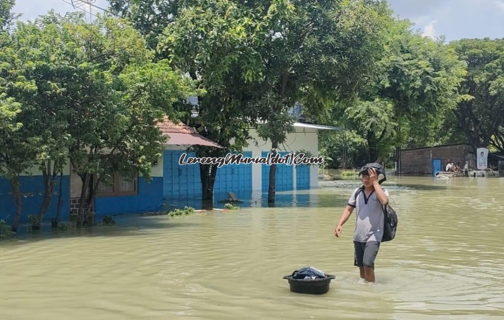 Seorang pengungsi membawa ember yang berisi pakaian