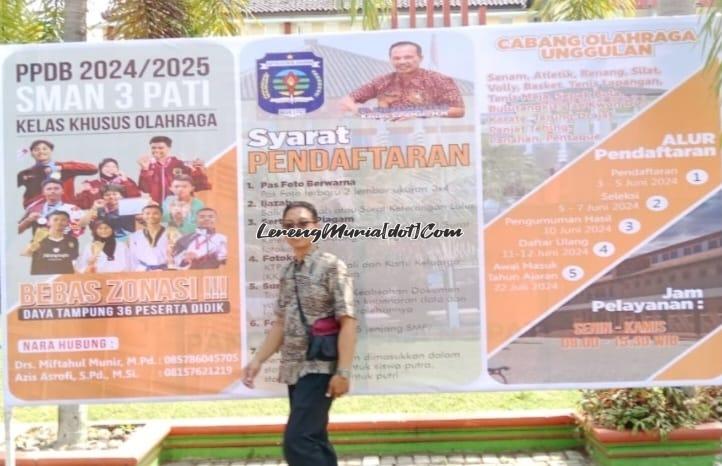 Seorang warga sedang lewat di depan banner PPDB  KKO SMAN 3 Pati yang sudah terpasang