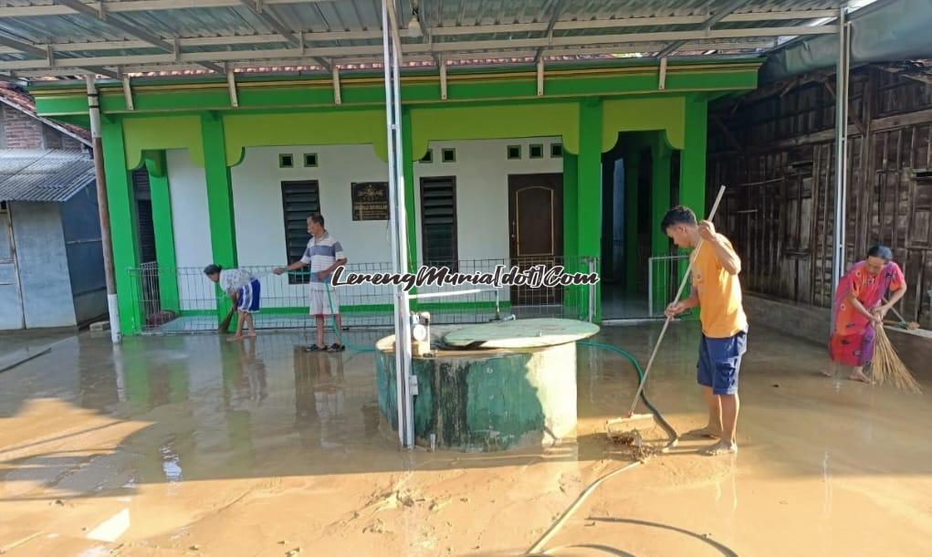 Warga Desa Angkatan Kidul Pati sedang membersihkan lumpur di depan salah satu mushola akibat tergenang banjir semalam