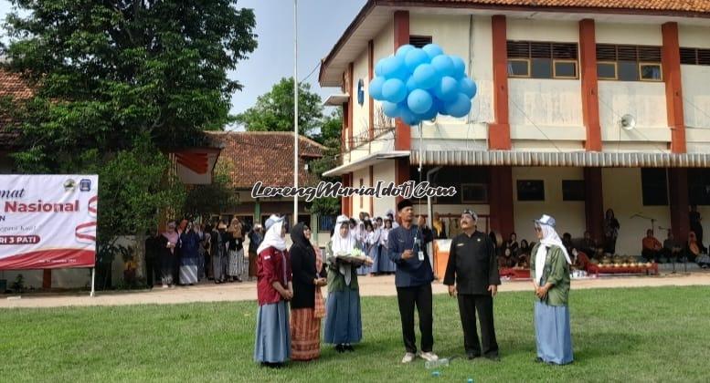 Plt. Kepala SMAN 3 Pati Kaslan, S.Pd. Mat., M.M. memotong balon biru dalam peringatan HGN 2024 di lapangan upacara