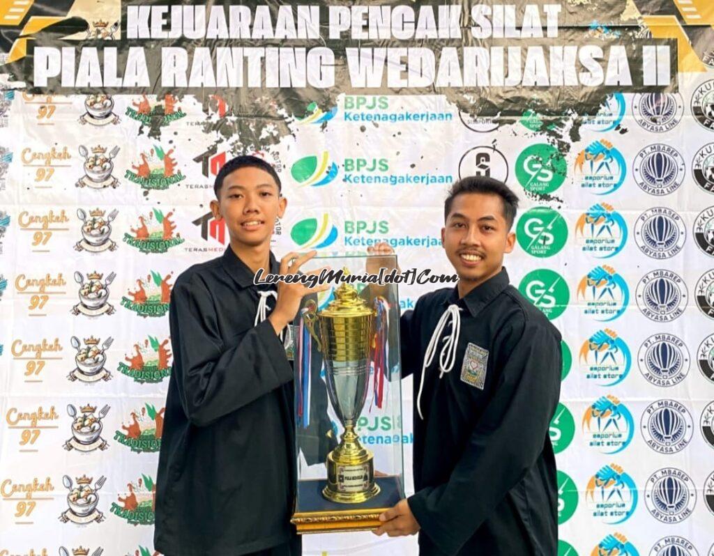 Fajar Hamzah, M.Or. (kanan) selaku ketua panitia menyerahkan piala juara umum 1 kepada Javier Maulana Akbar (kiri) sebagai perwakilan official Ranting Wedarijaksa