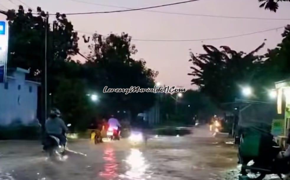 Pengendara sepeda motor melewati genangan banjir di jalan raya Desa Angkatan Lor Pati