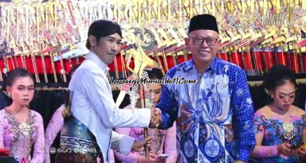 Dalang Ki Sigid Ariyanto (kiri) menerima tokoh wayang Ontoseno dari Kepala Desa Kunjeng Ahmad Rifa'i (kanan) dalam pentas wayang kulit sedekah bumi
