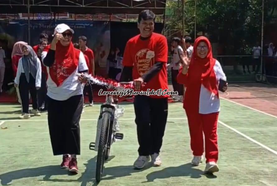 Yuli Sudargini (kiri) selaku Kepala SMAN 3 Pati menyerahkan sepeda federal kepada Machfud Ardi (tengah) sebagai pemenang hadiah utama didampingi Jumiarsih (kanan) selaku Waka Humas